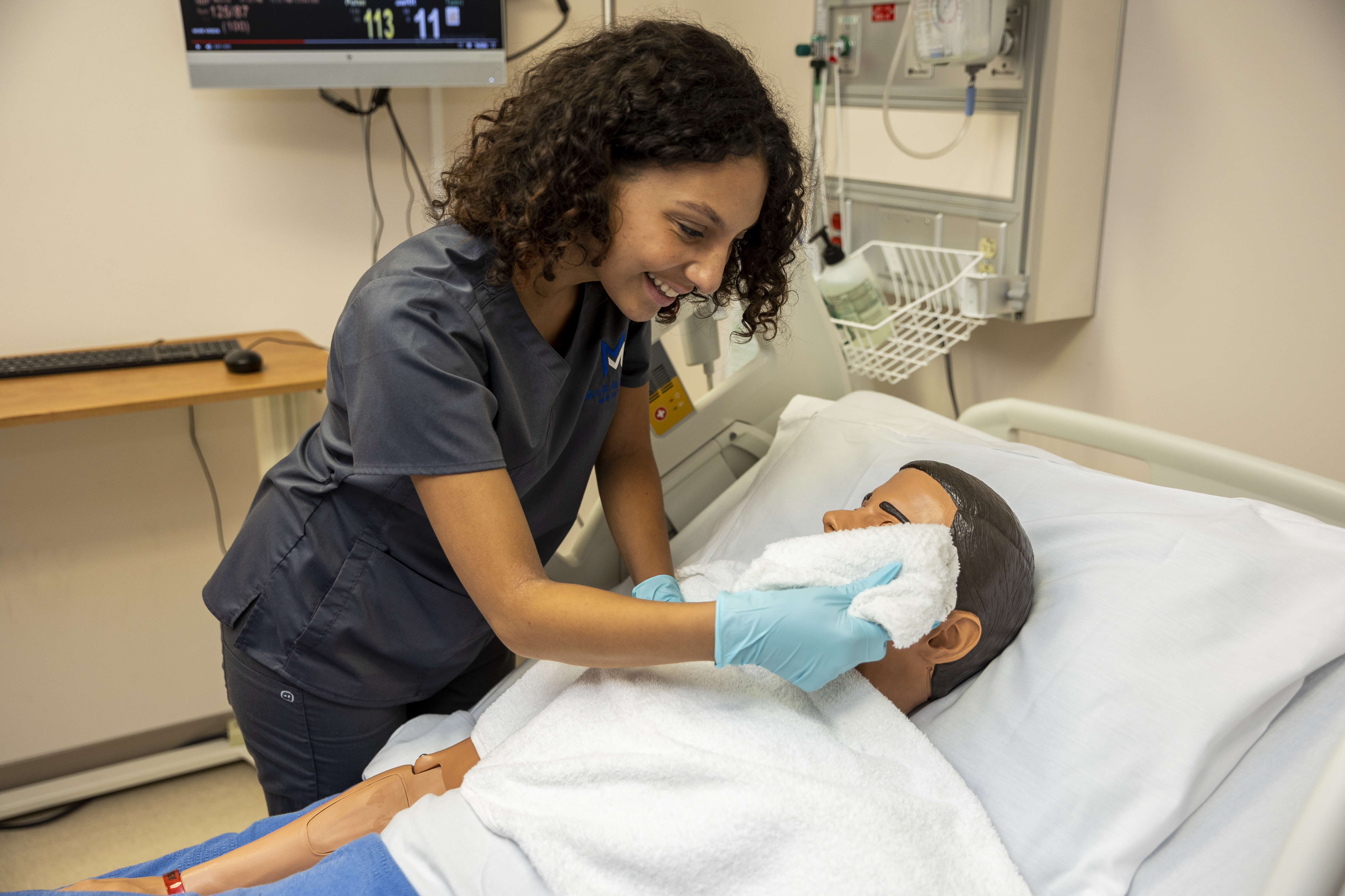 CNA student assisting a patient mannequin with facial hygiene