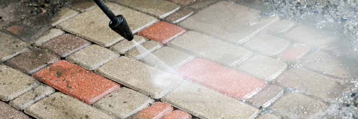 Pressure washing brick paver patio to remove dirt and grime.
