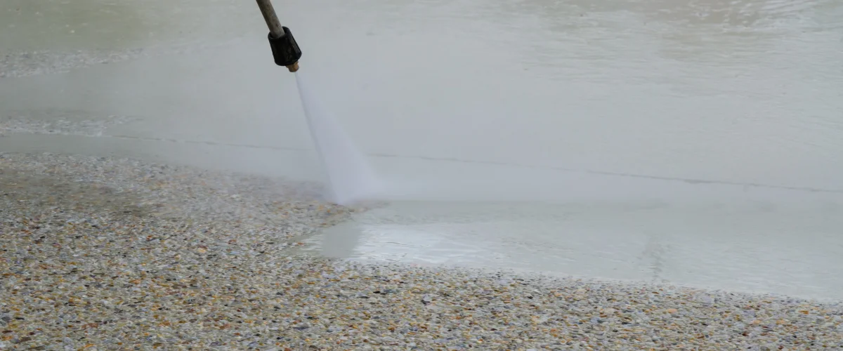 A close-up shot of a power washer cleaning a dirty sidewalk, with a stream of water hitting the concrete. A close-up shot of a power washer cleaning a dirty sidewalk, with a stream of water hitting the concrete.