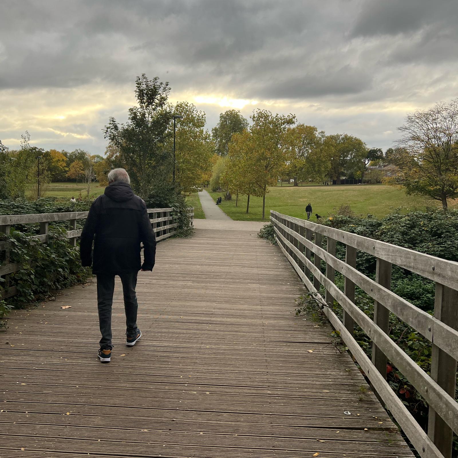 A person walking forward alone on an open path, viewed from behind.