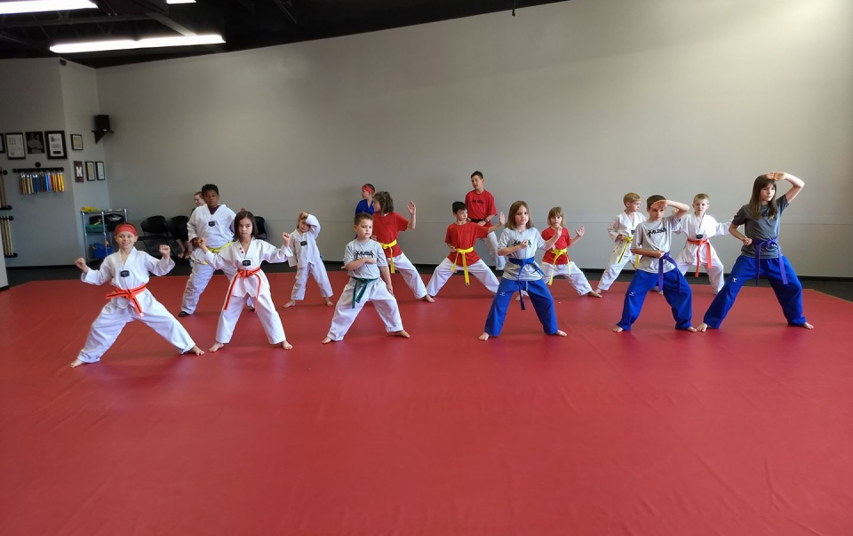 A group of children training martial arts, performing stances at Musa Sherwood Martial Arts.