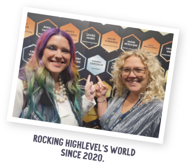 Cathy and Julie pointing at Funnel Gorgeous's spot as one of the first Diamond award recipients on the wall of SaaSpreneur awards at the 2020 Highlevel Level Up event.