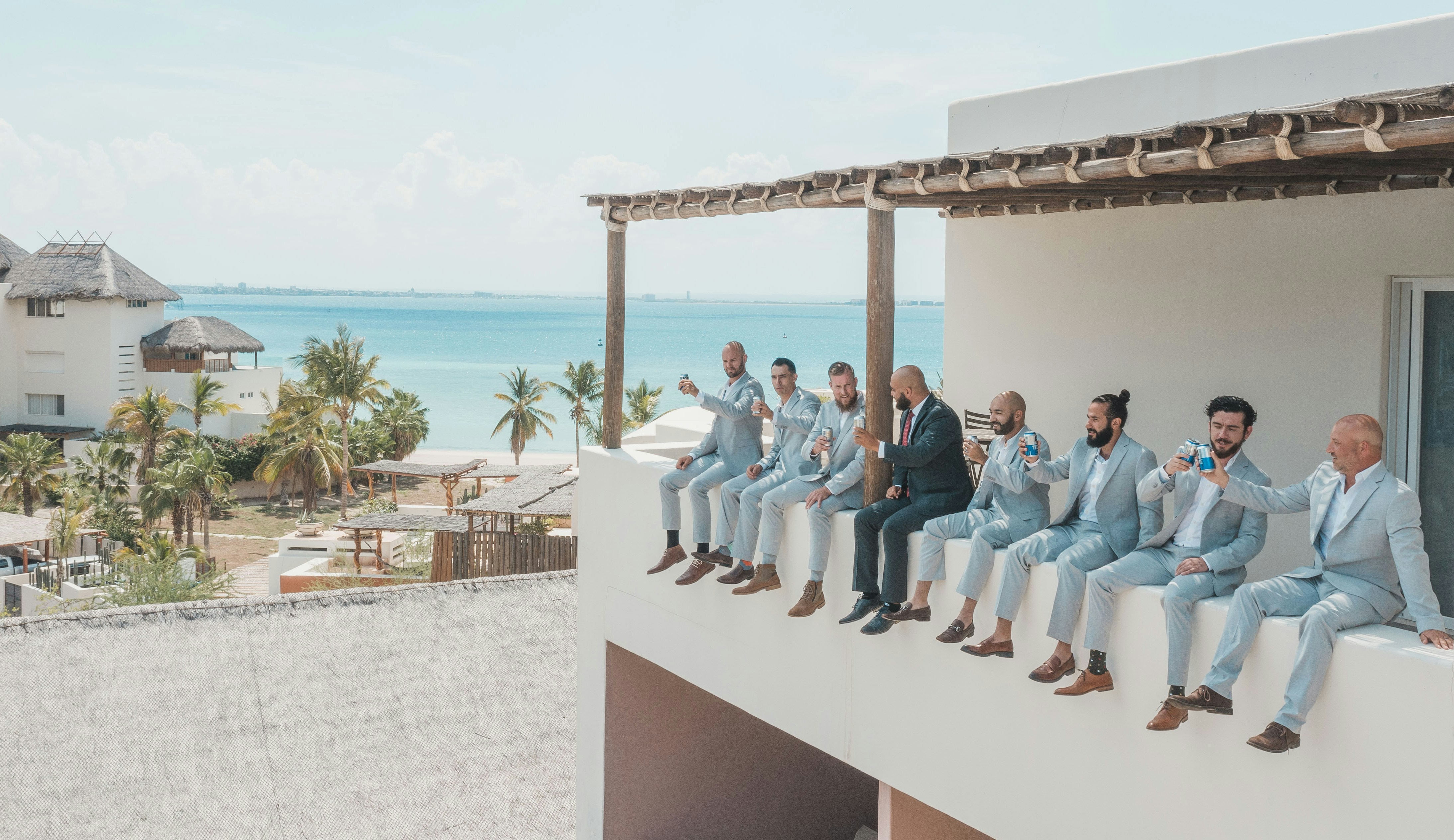 Groom and groomsmen in coordinated light blue custom suits celebrating at a destination wedding