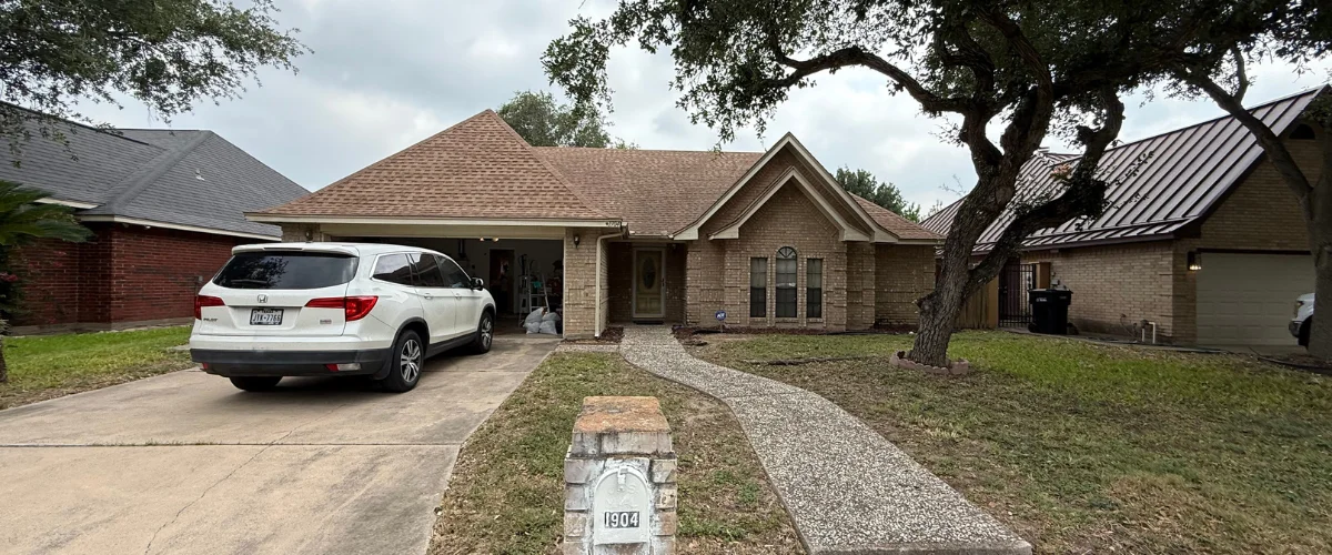 A suburban brick home with a warm brown roof, a white SUV parked in the driveway, and a winding concrete path. A suburban brick home with a warm brown roof, a white SUV parked in the driveway, and a winding concrete path.