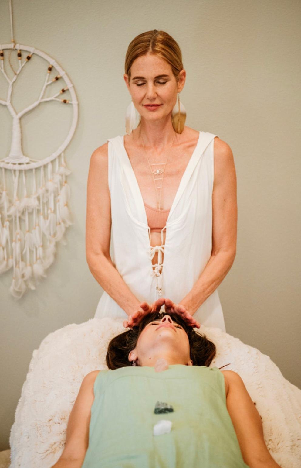 Sandra giving Reiki to a woman lying on a treatment table