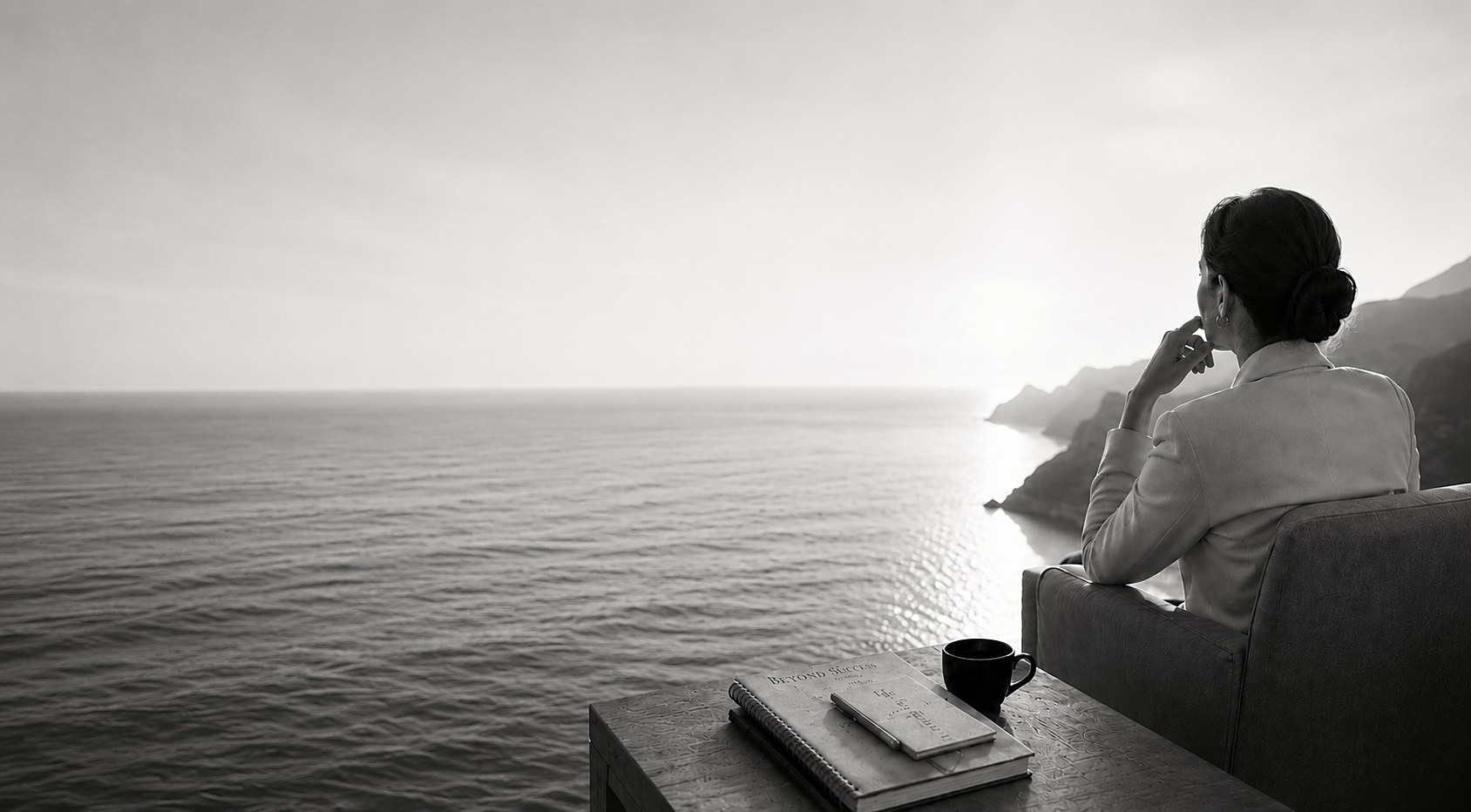 Dona directiva contemplant el mar a l'alba, amb el quadern Beyond Success — The Integral Life Design Method