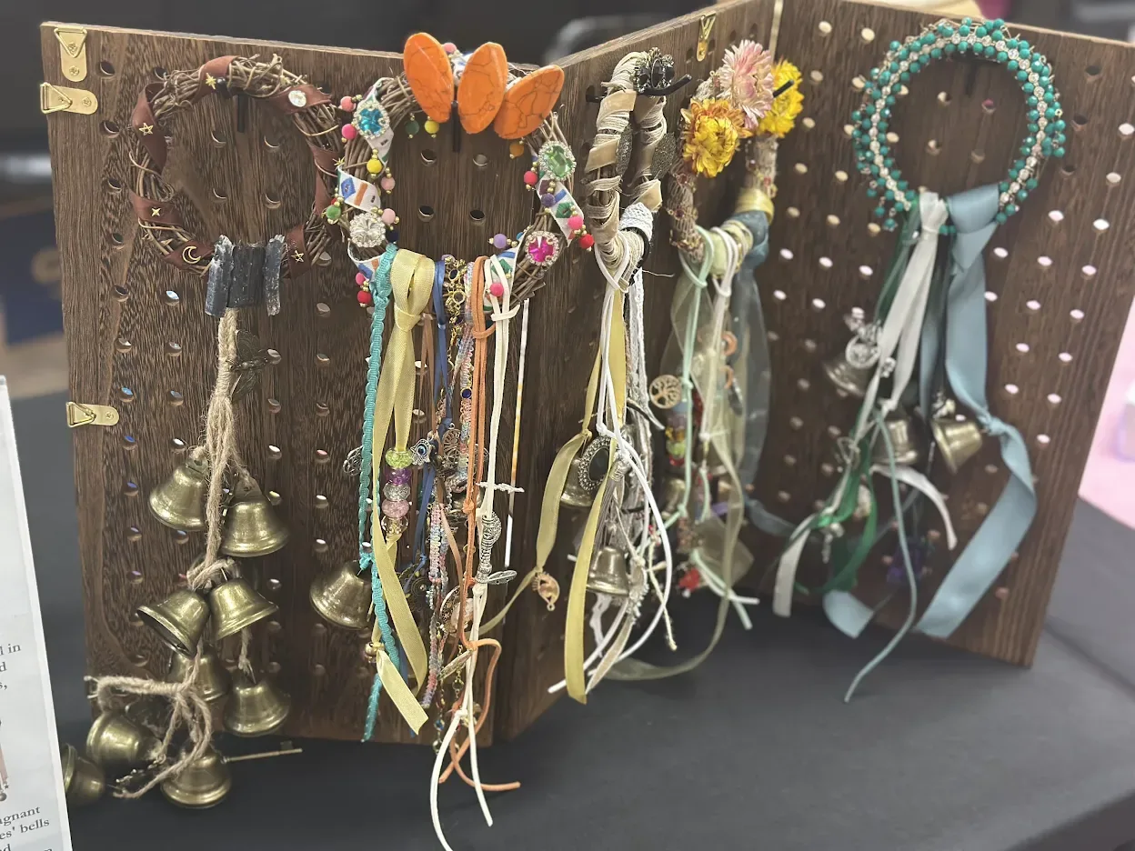 The Alter & Amulet pegboard at a market, with five handmade witch bells hanging in a row