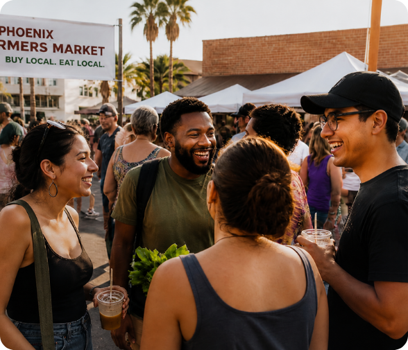 Photograph of diverse people smiling and talking at a sunny outdoor Phoenix farmers market.
