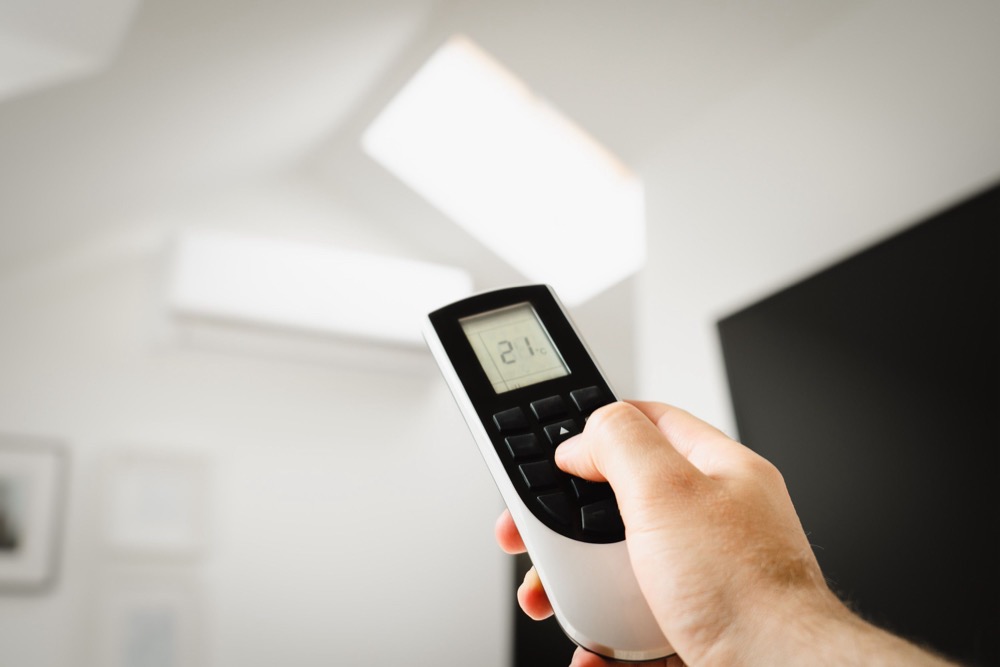 Homeowner adjusting air conditioning with a remote control