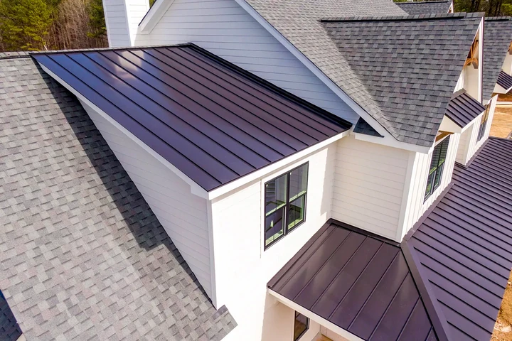Home with asphalt shingles and dark standing-seam metal roof sections