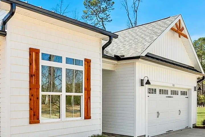 White horizontal siding with black gutters and wood window shutters