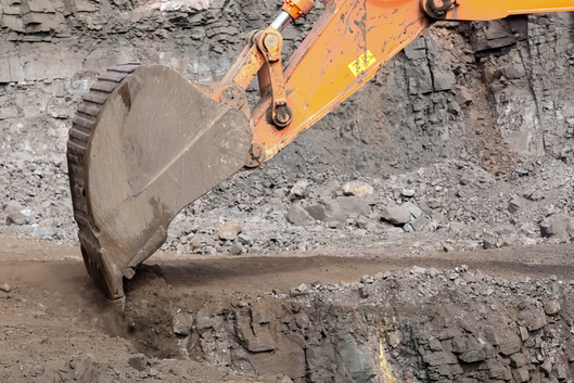 Baggerlöffel hebt Erdreich aus Baugrube für Fundament bei Erdarbeiten