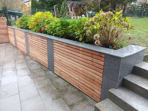 Mauer mit horizontalen Holzlamellen auf Betonsockel neben Außentreppe als moderner Sichtschutz