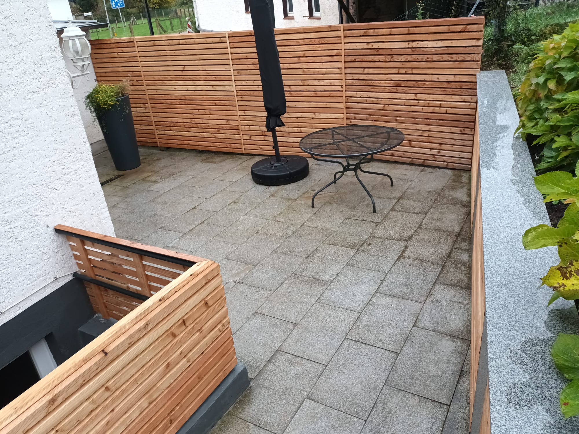 Holz-Sichtschutz auf Terrasse mit Ecklösung und integrierter Bank vor Hauswand