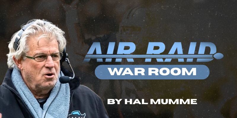 Coach Mills explaining a route concept in front of a film wall, documentary style portrait.