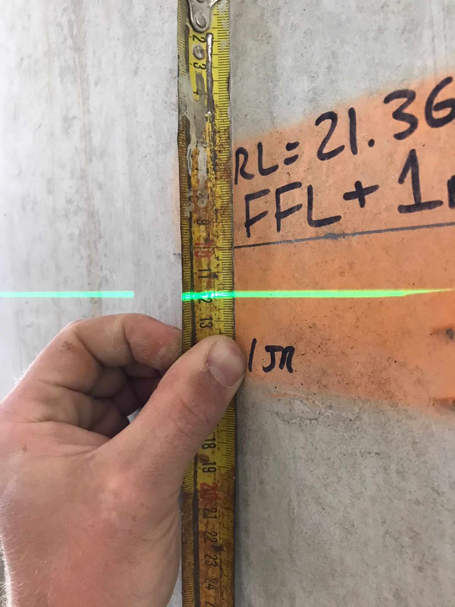 A tape measure held against a finished floor level datum marked on the wall