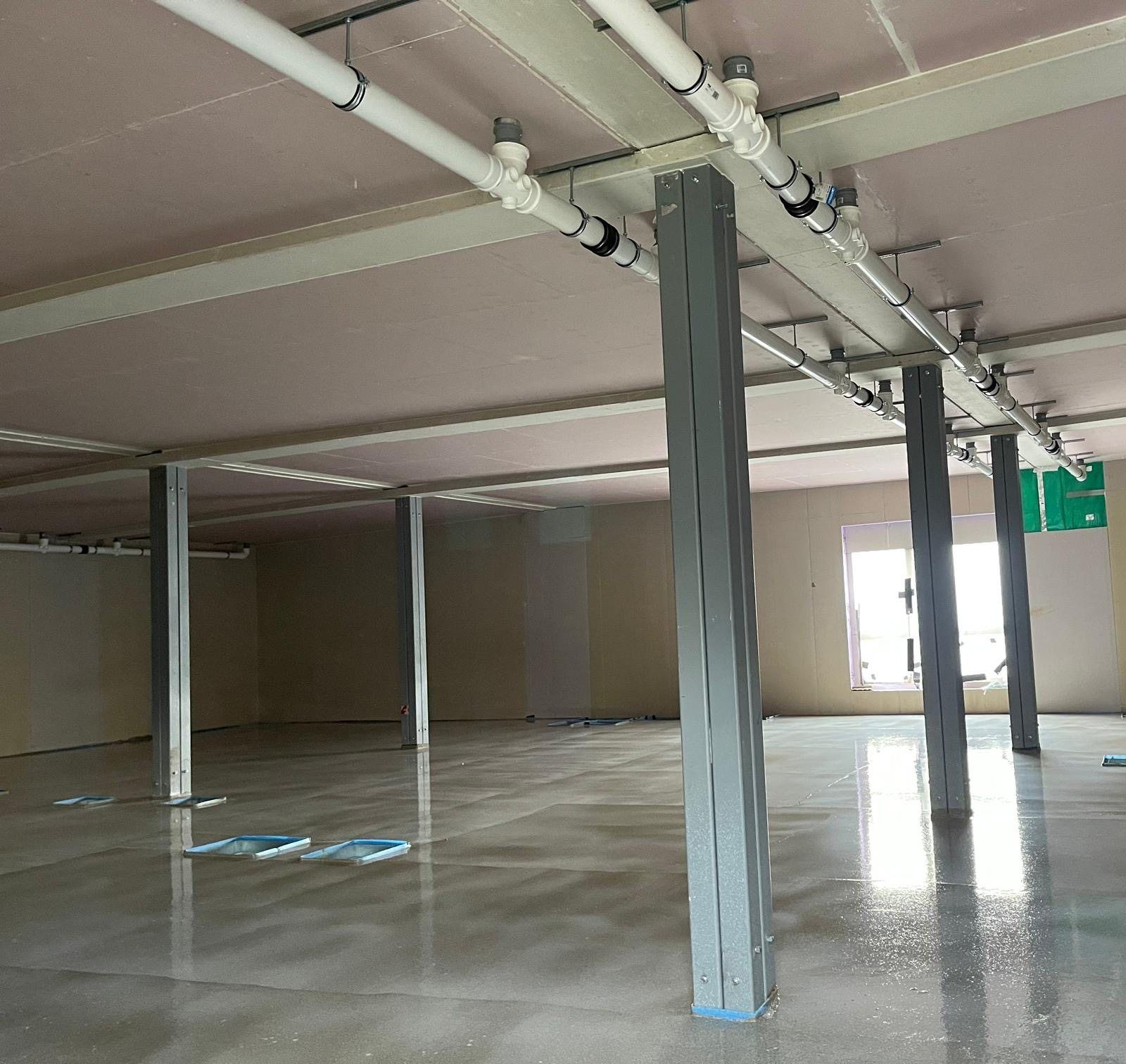 A finished screed floor around structural columns in an open-plan space