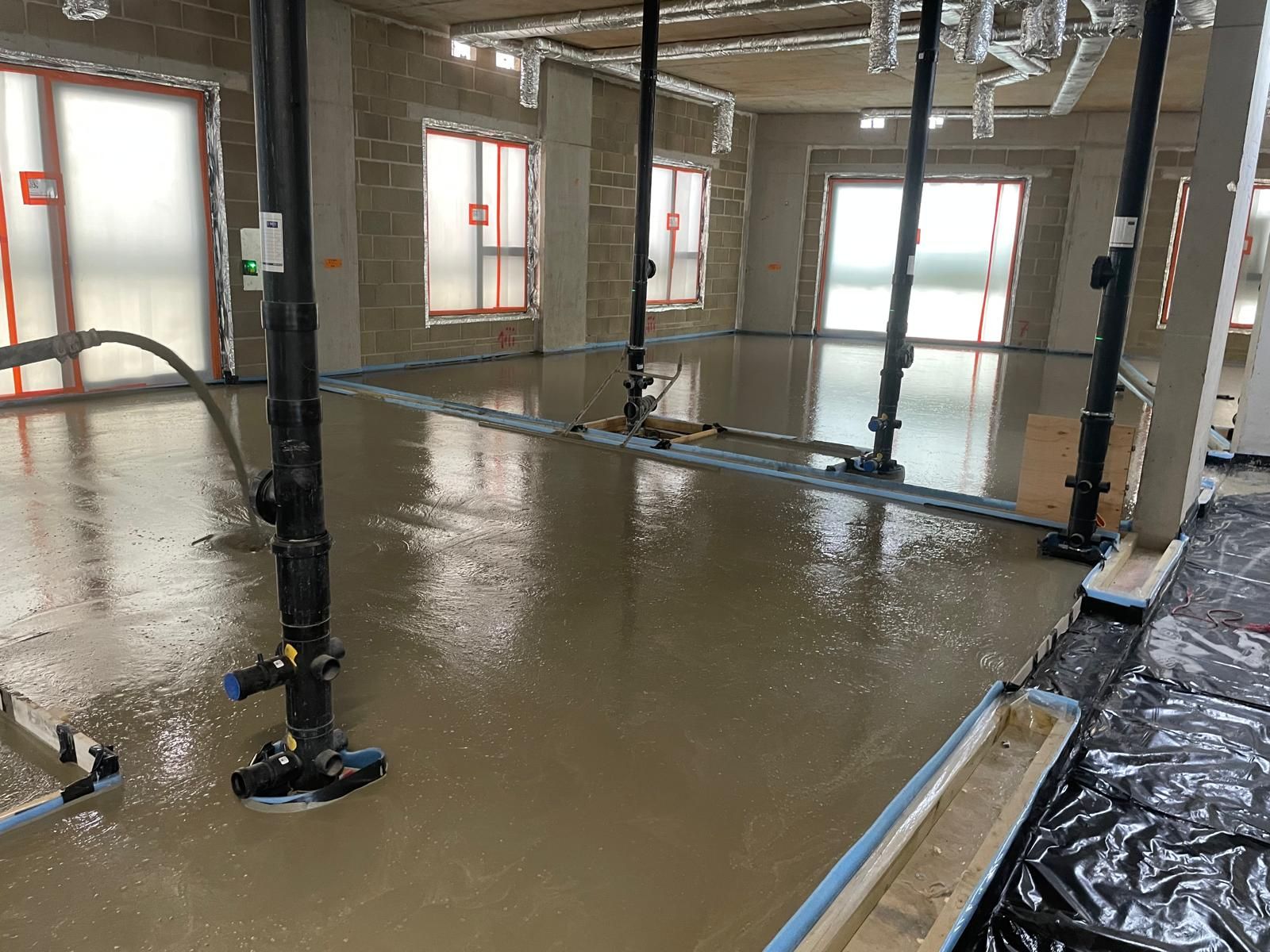Flowing screed being pumped across an open floor plate at Brentford Lock