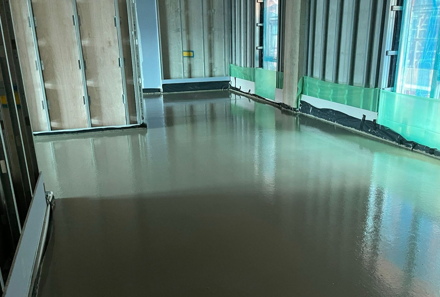 A flowing screed floor with a mirror-like wet finish reflecting a glazed wall