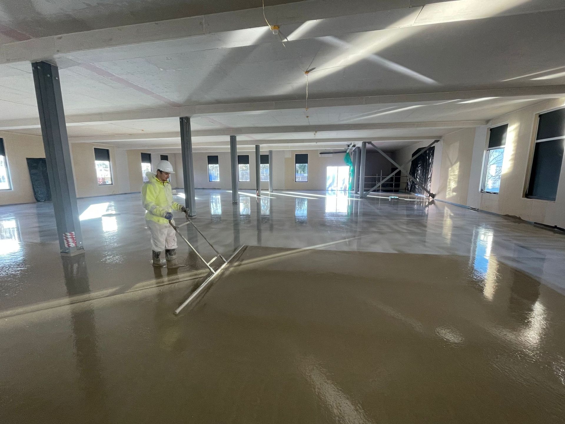 CSC Screeding operative levelling Tarmac TopFlow Horizontal flowing screed with a dappling bar at Royal Berkshire Hospital for MTX Contractors