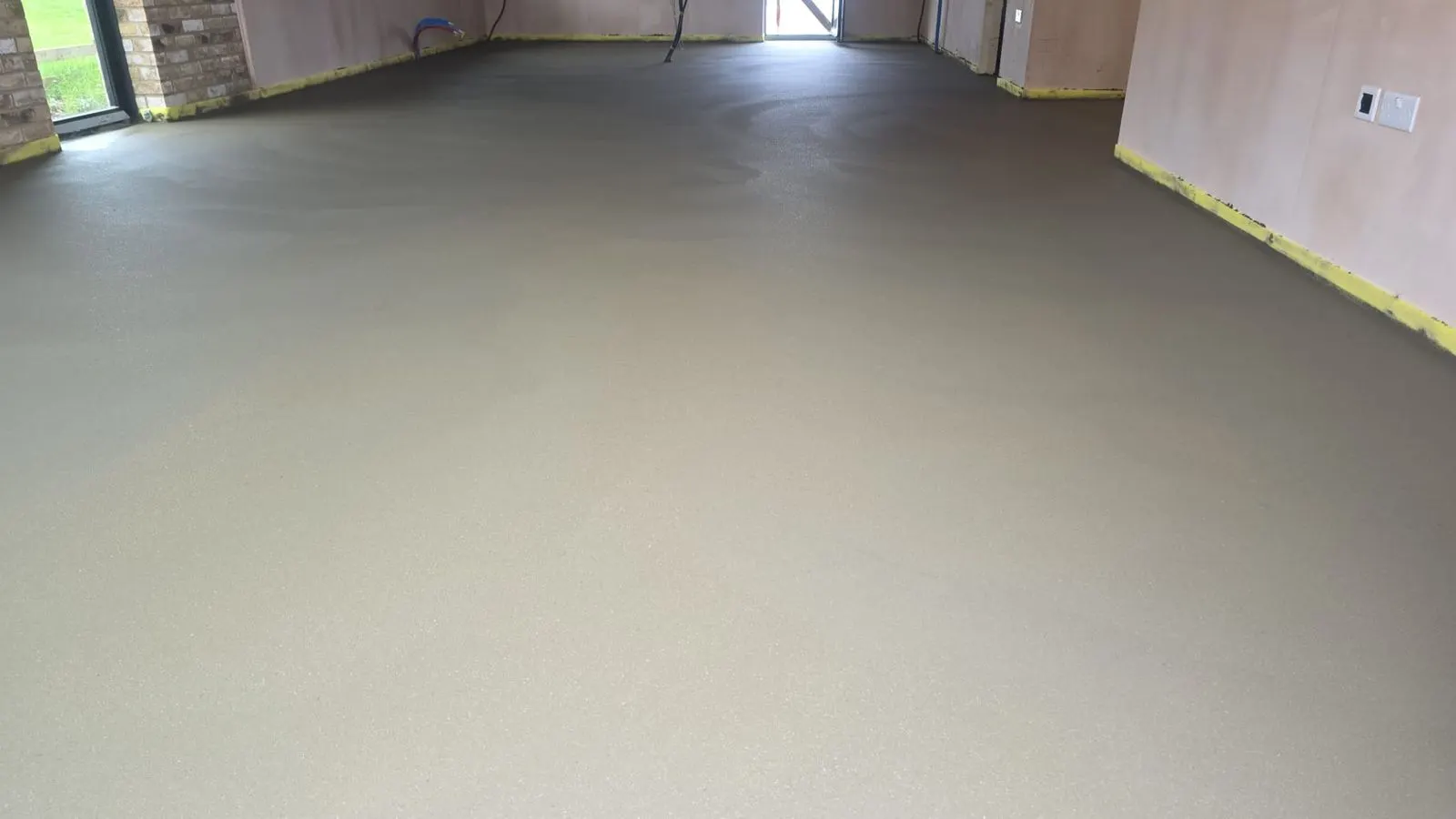 Freshly laid smooth screed floor across an open-plan room ready for testing