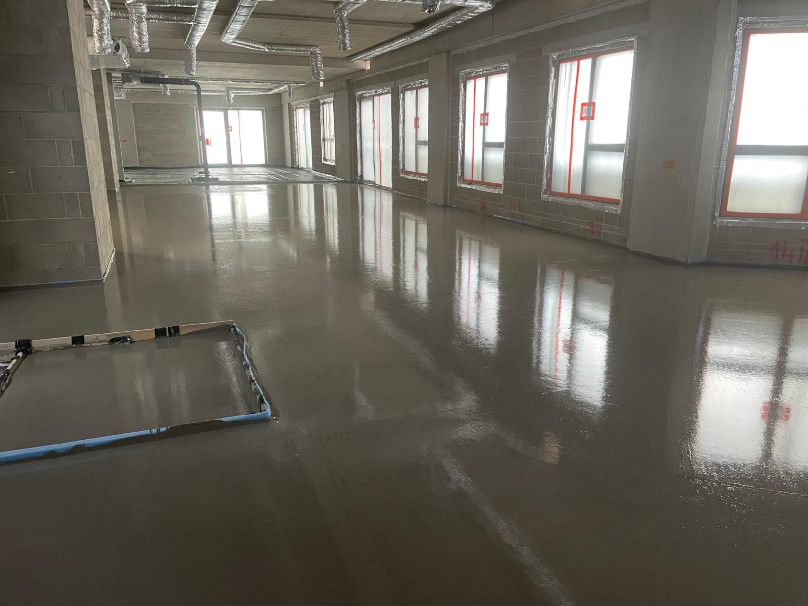 A flowing screed floor showing levelling pins and a smooth glossy surface at Brentford Lock
