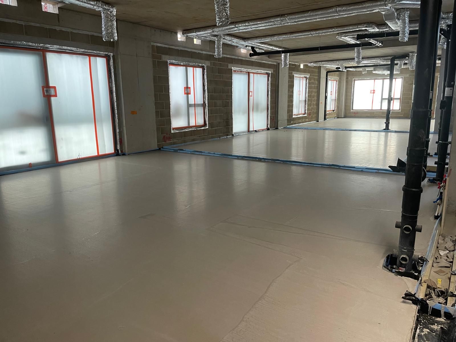 A wide finished flowing screed floor plate lined with windows at Brentford Lock