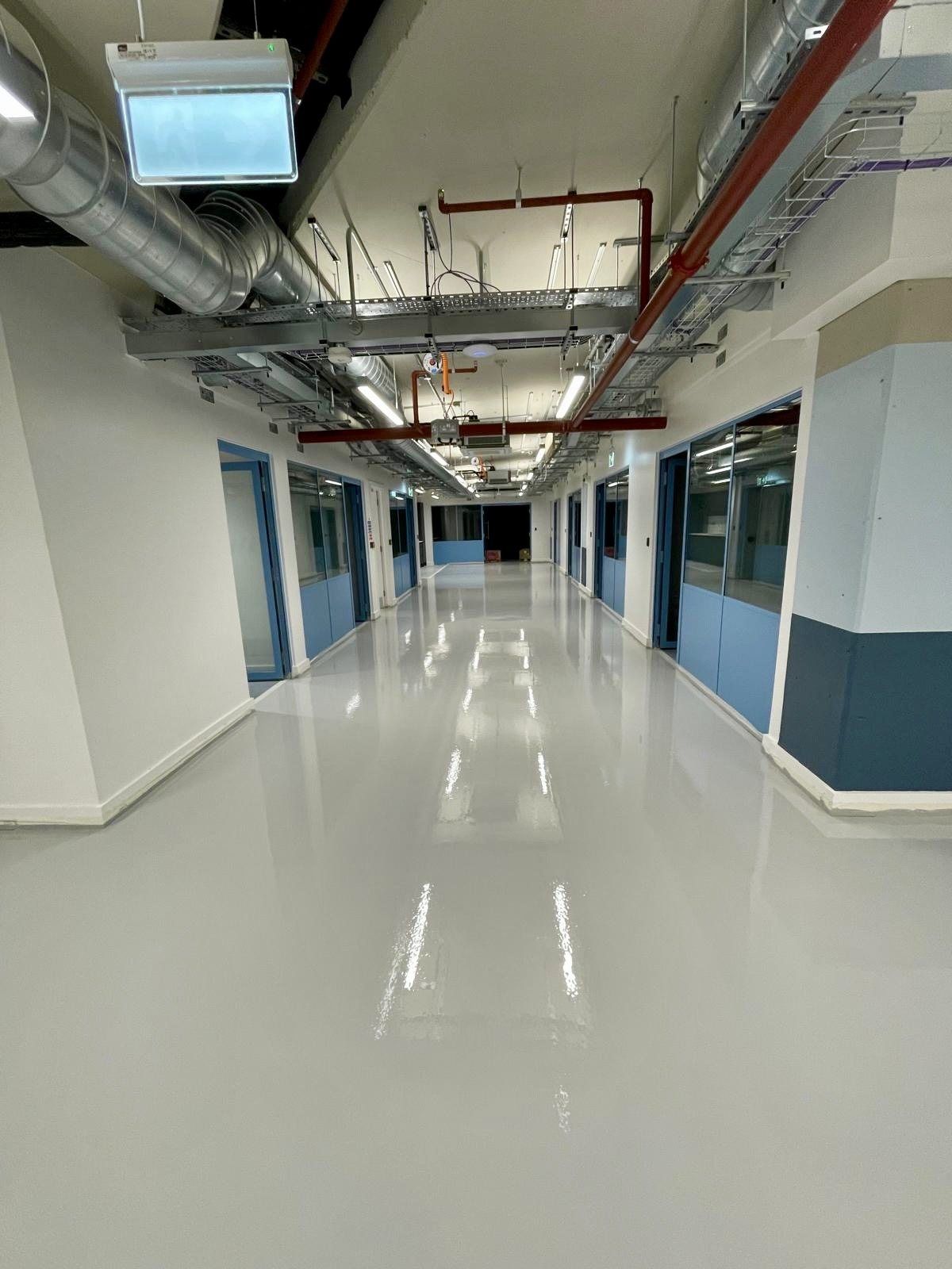 A long commercial corridor with a bright, finished screed floor