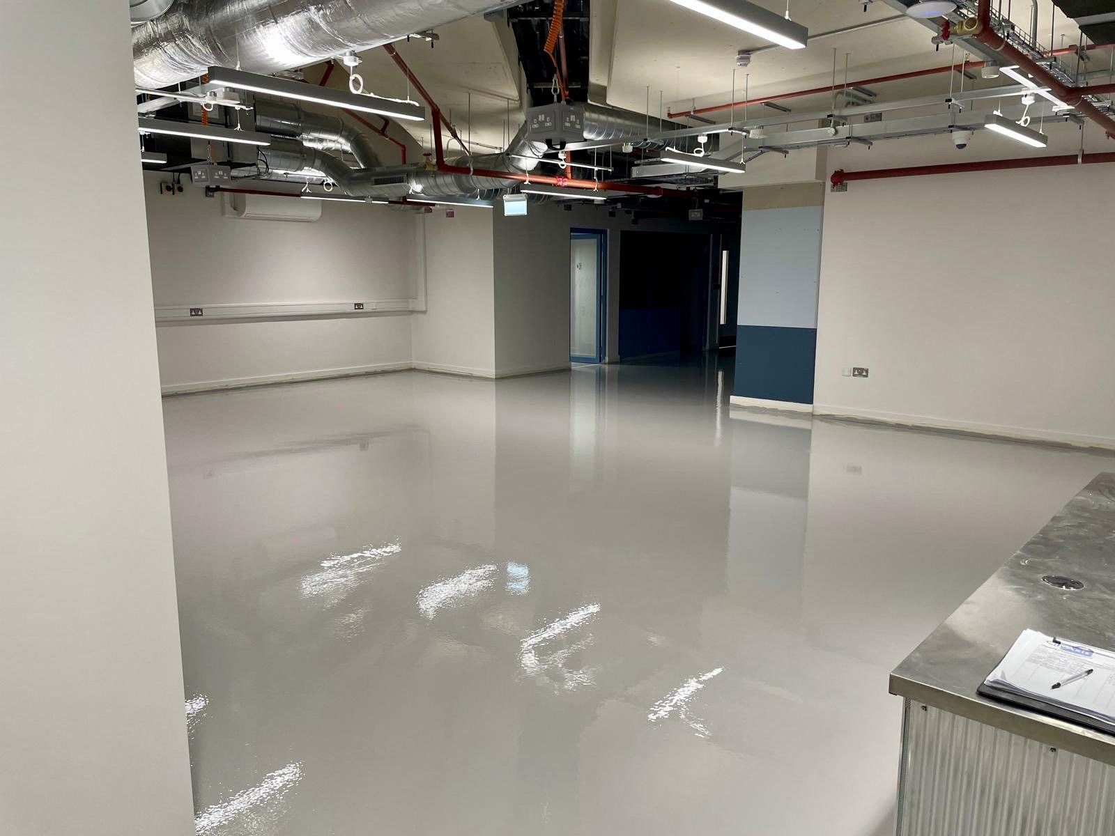 A large finished screed floor in a commercial building with exposed services overhead