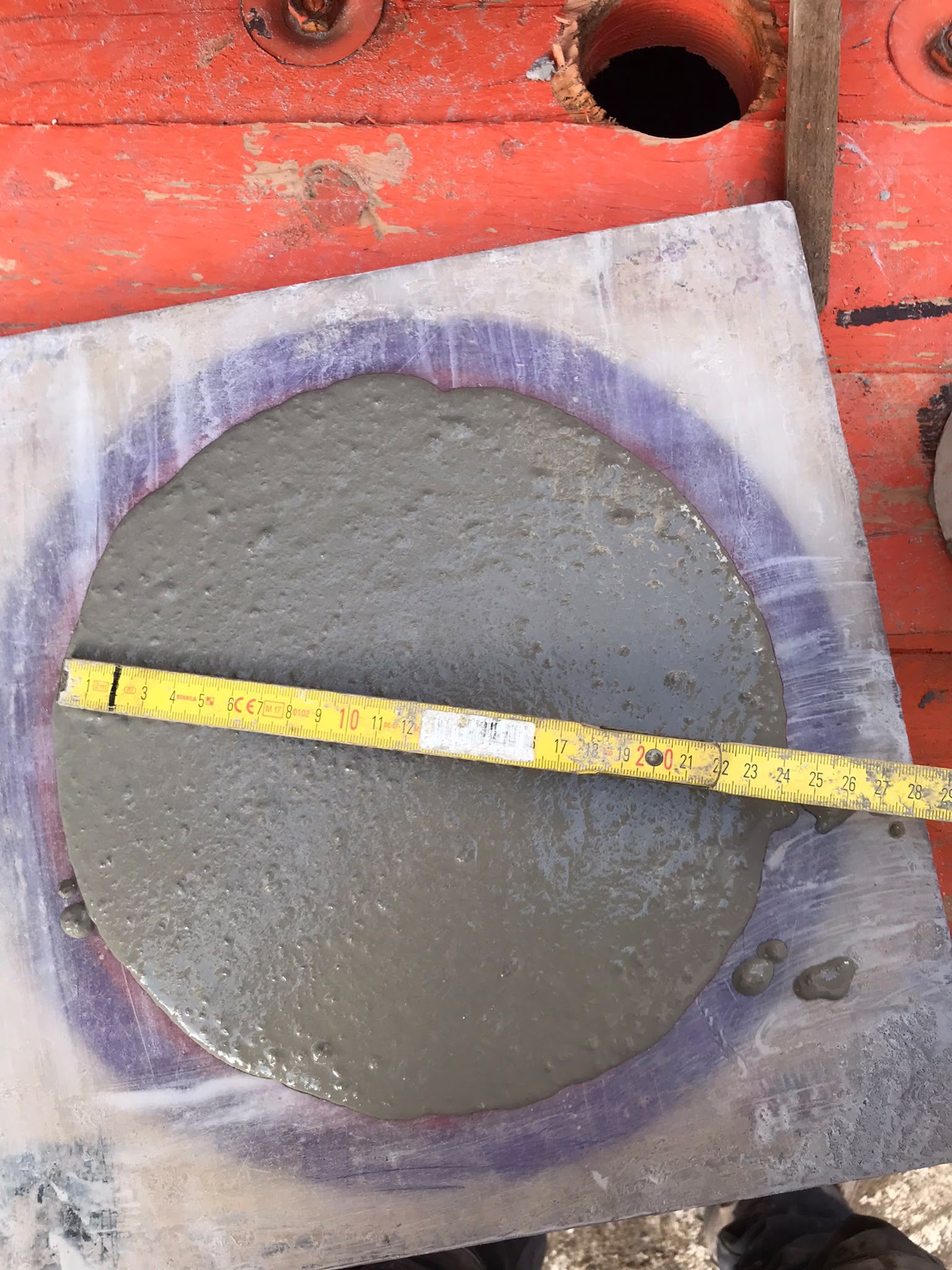 A flow-ring test with a tape measure across the spread of flowing screed at Brentford Lock