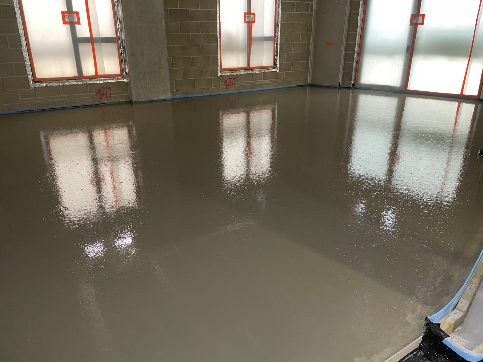 A freshly finished glossy flowing screed floor reflecting the windows at Brentford Lock