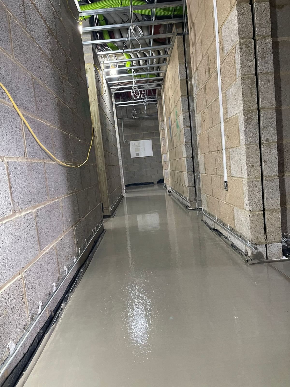 A narrow residential corridor with a finished flowing screed floor