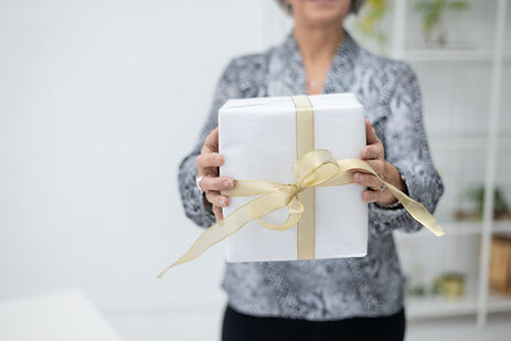 Woman holding a white gift box with a gold ribbon and bow. Woman holding a white gift box with a gold ribbon and bow.