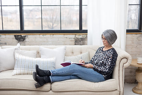 Woman relaxing on a sofa while reading and taking notes in a notebook. Woman relaxing on a sofa while reading and taking notes in a notebook.