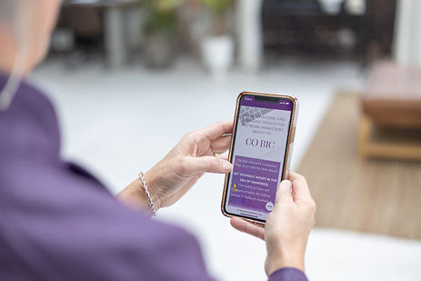 Person holding a smartphone displaying a purple-themed webpage. Person holding a smartphone displaying a purple-themed webpage.