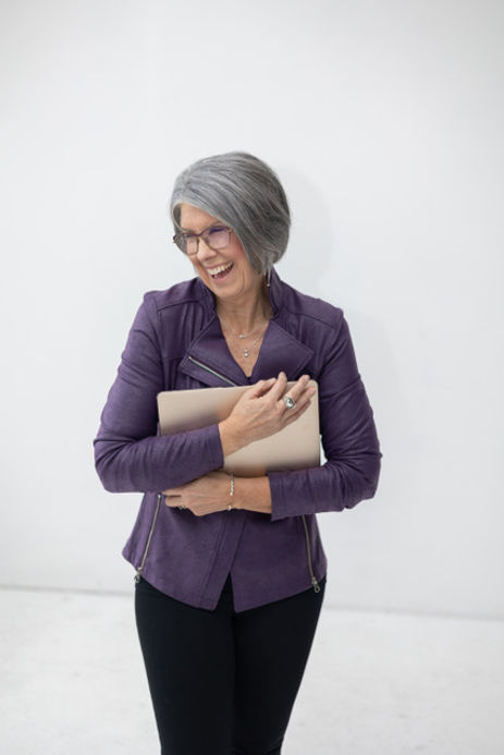 Smiling woman in a purple jacket holding a tablet. Smiling woman in a purple jacket holding a tablet.