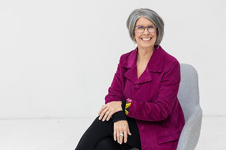 Smiling woman in a magenta jacket seated in a chair. Smiling woman in a magenta jacket seated in a chair.