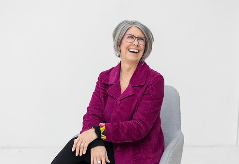 Smiling woman in a magenta jacket seated in a chair Smiling woman in a magenta jacket seated in a chair