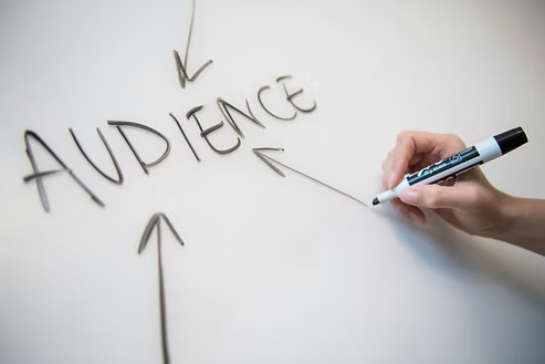 Hand writing the word “AUDIENCE” on a whiteboard with arrows pointing toward it. Hand writing the word “AUDIENCE” on a whiteboard with arrows pointing toward it.