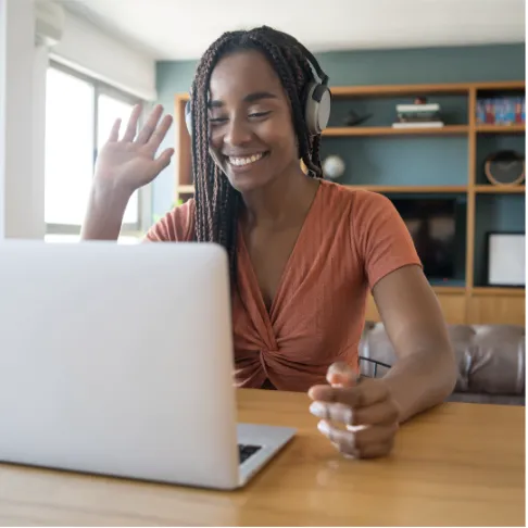 Smiling teacher waving at her laptop during a video call