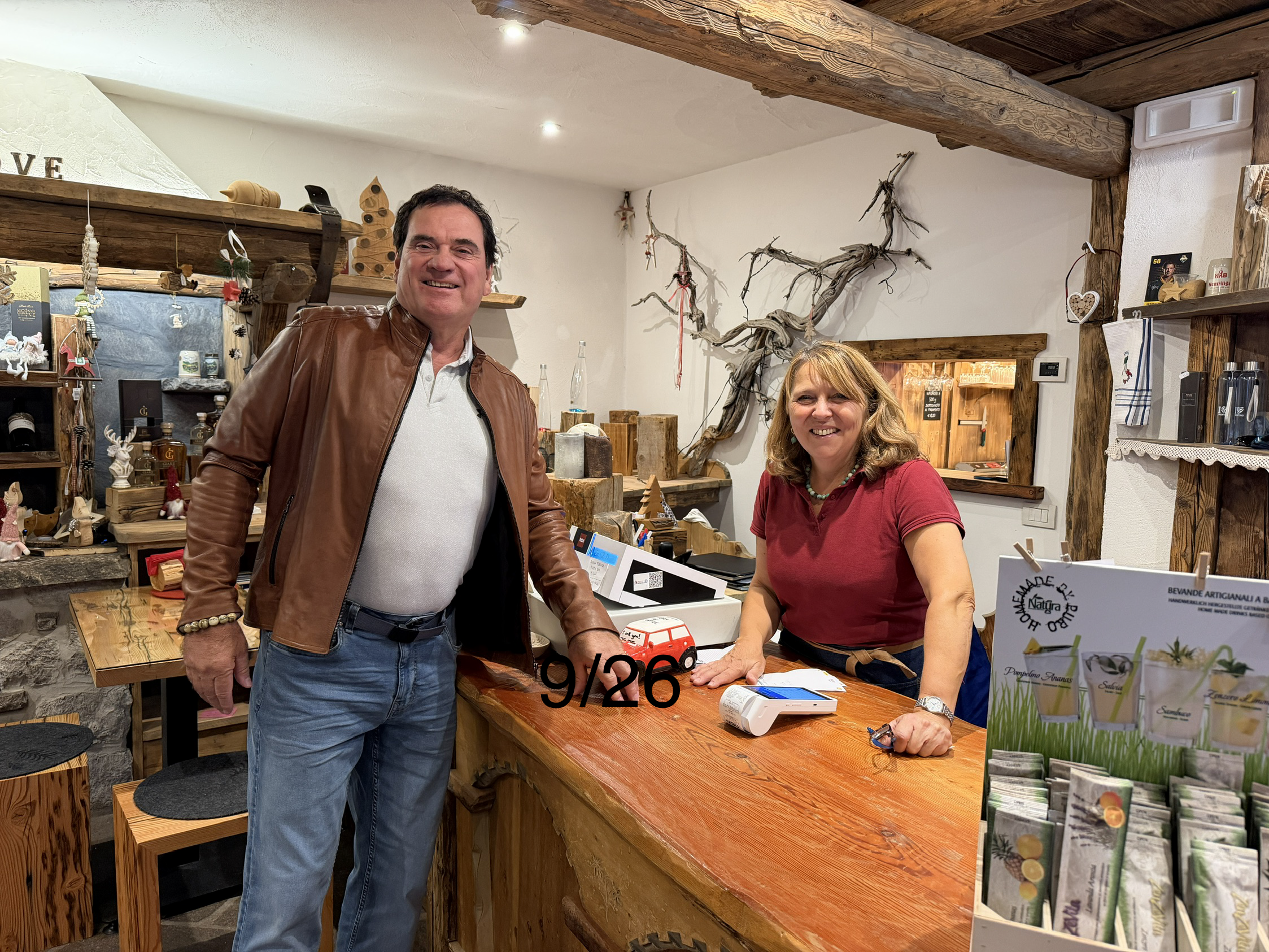 RepuBoostAI founder David standing with a café owner behind a wooden counter, with drinks and gifts on display