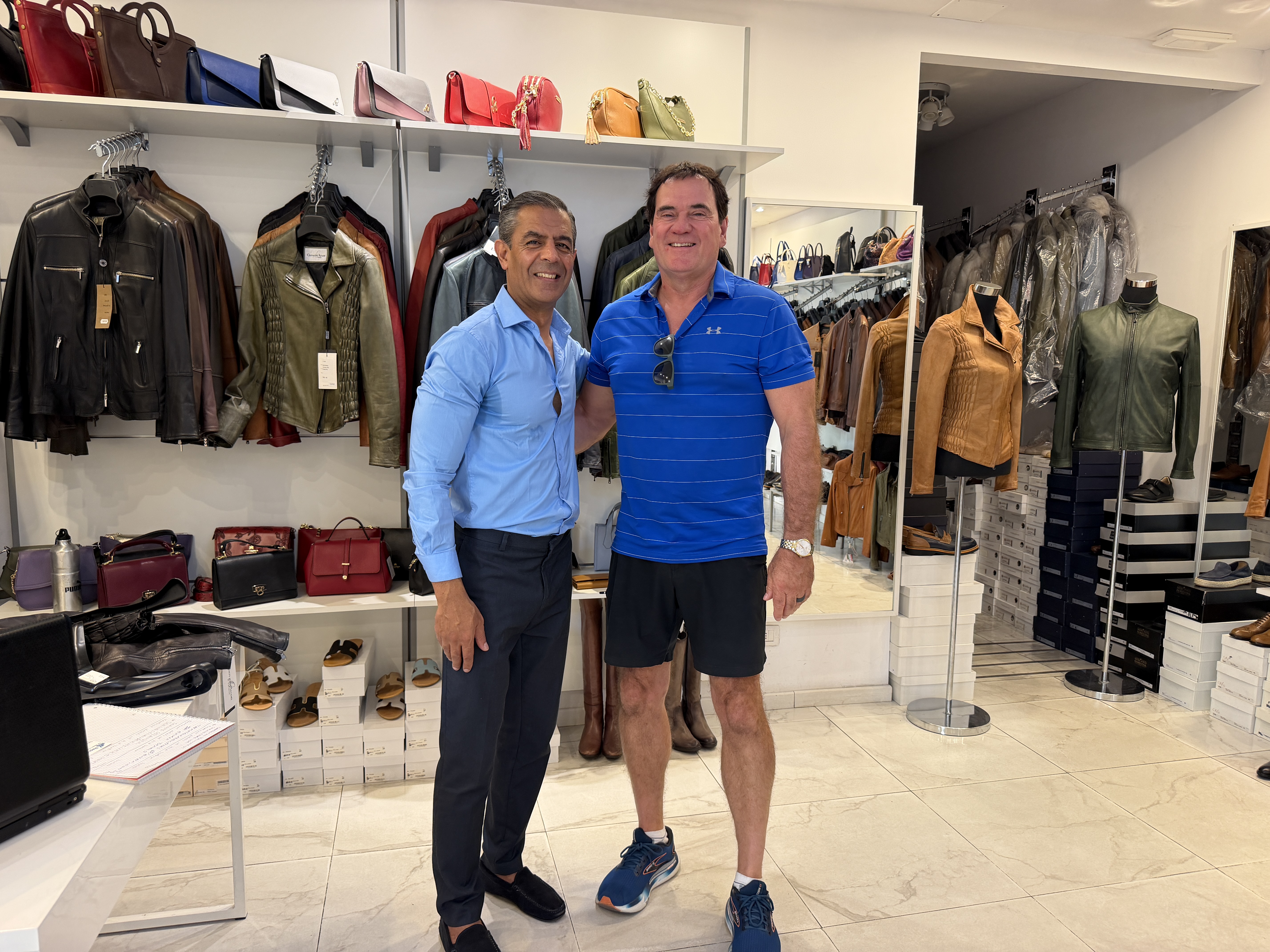 RepuBoostAI founder David standing with a retail shop owner in a leather goods store, with jackets and handbags on display
