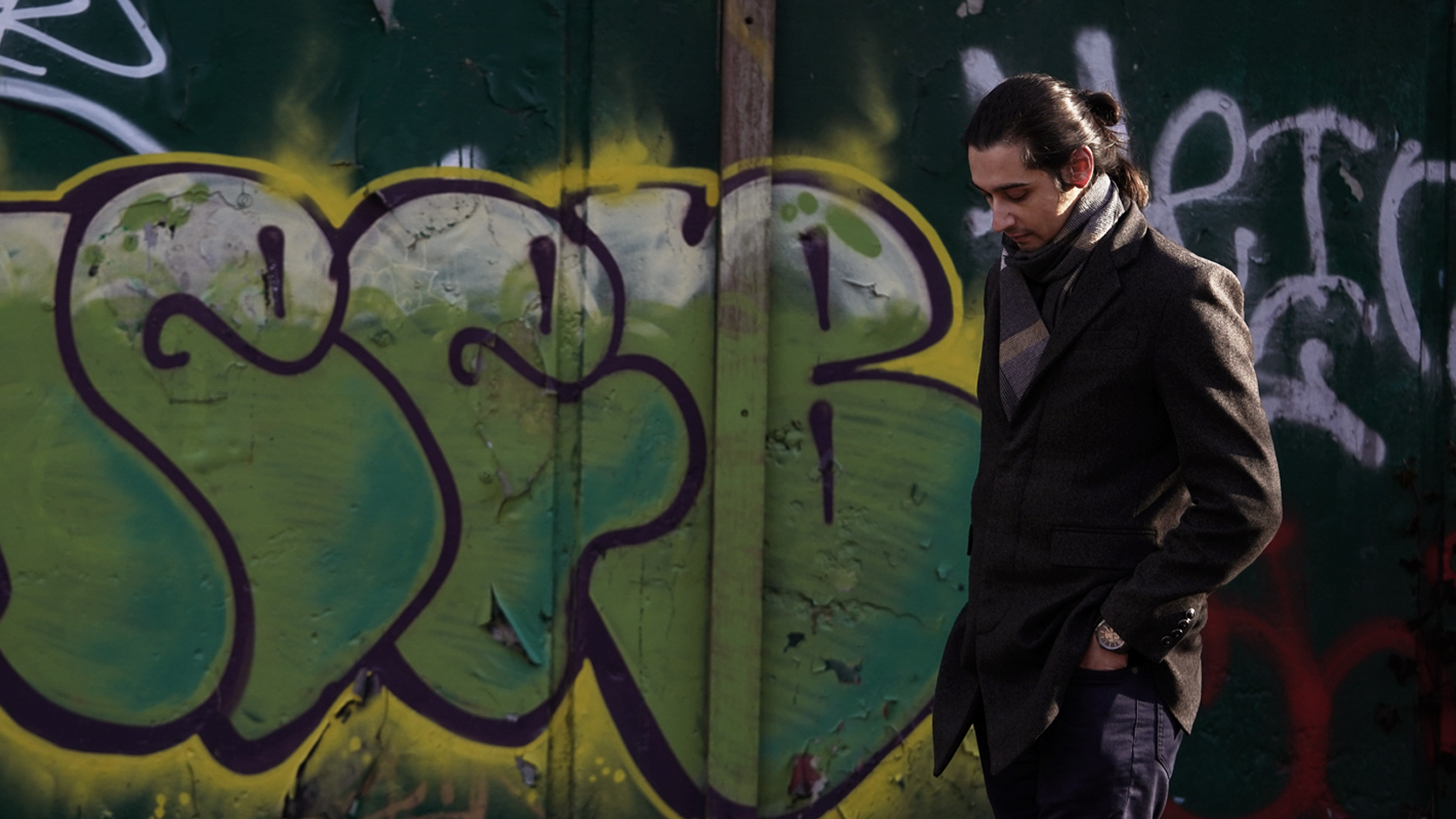 Johnny Pomykacz walking with graffiti in the background
