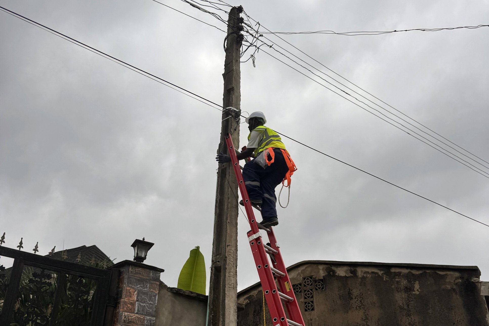 TEPA technician on a ladder installing overhead fiber cable on a pole