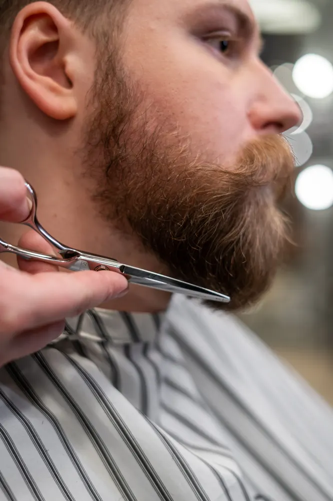 Barbier controleert het kapsel in de spiegel samen met de klant