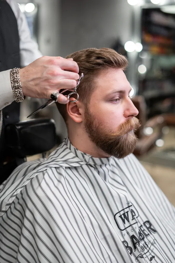 Barbier werkt met tondeuse aan een moderne haarstijl