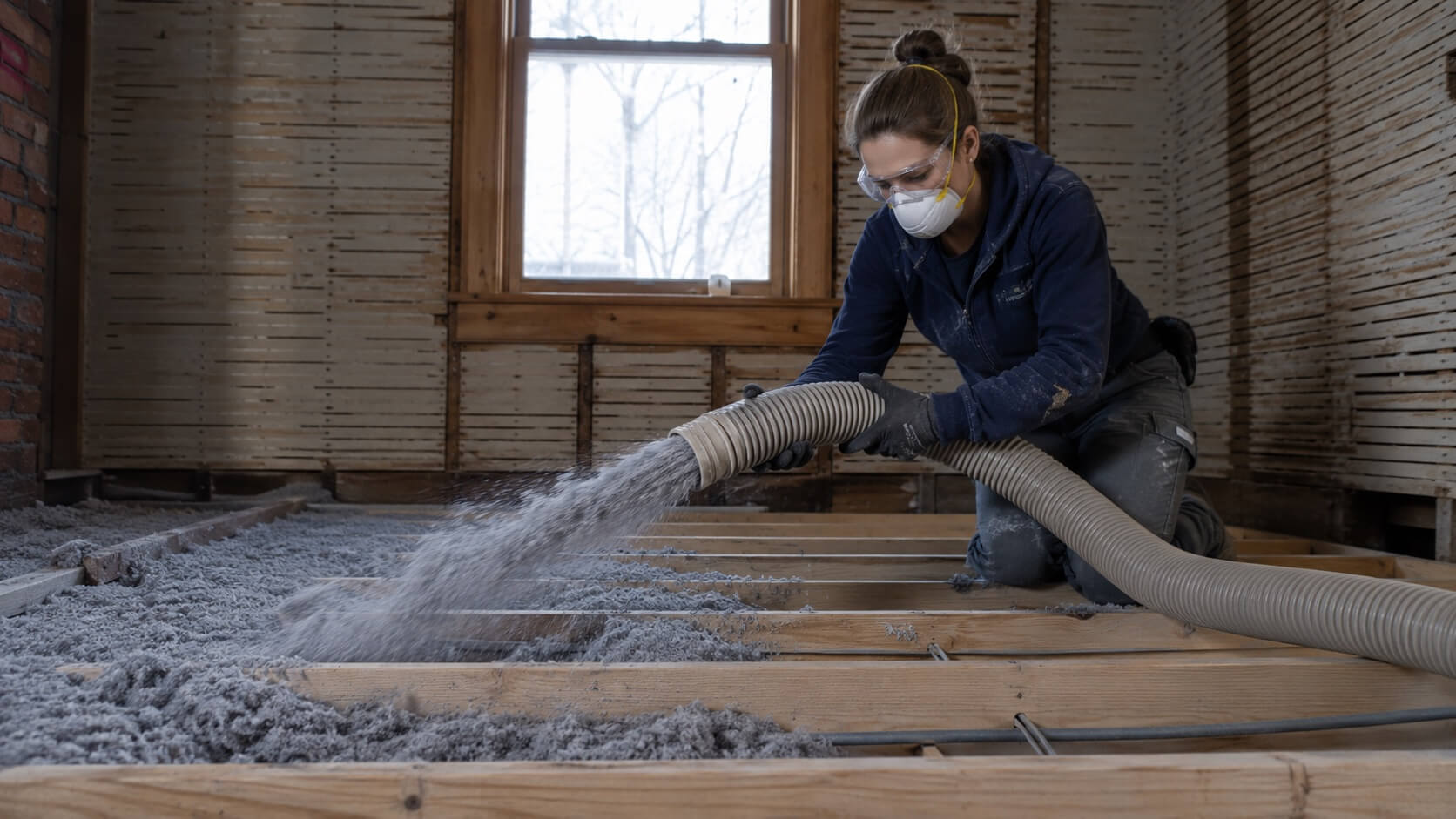 Woman blowing cellulose insulation into Kingston attic Woman blowing cellulose insulation into Kingston attic