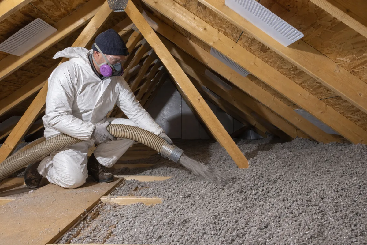 Installer adding loose-fill cellulose insulation to an attic