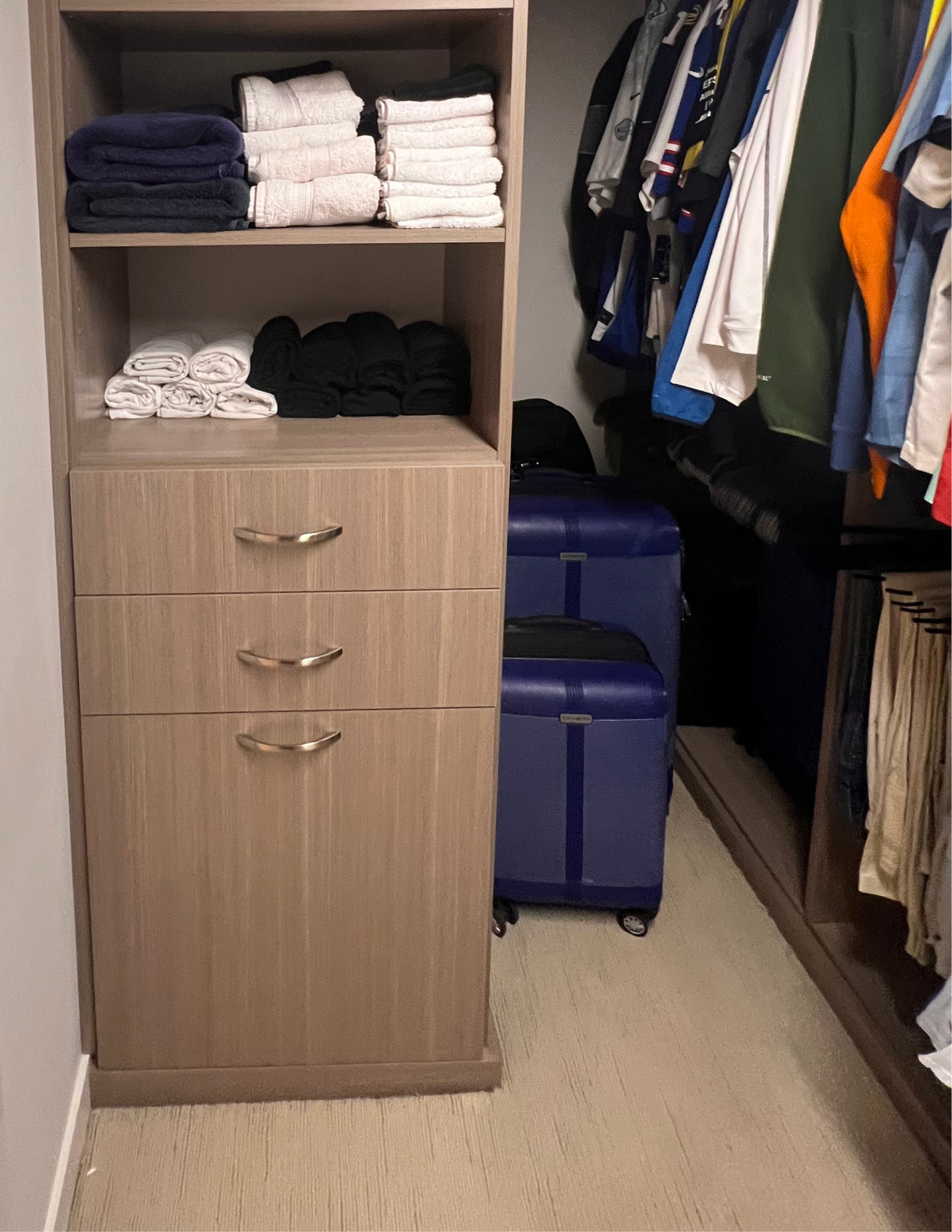  Closet with organized shelves, folded towels, and suitcases.