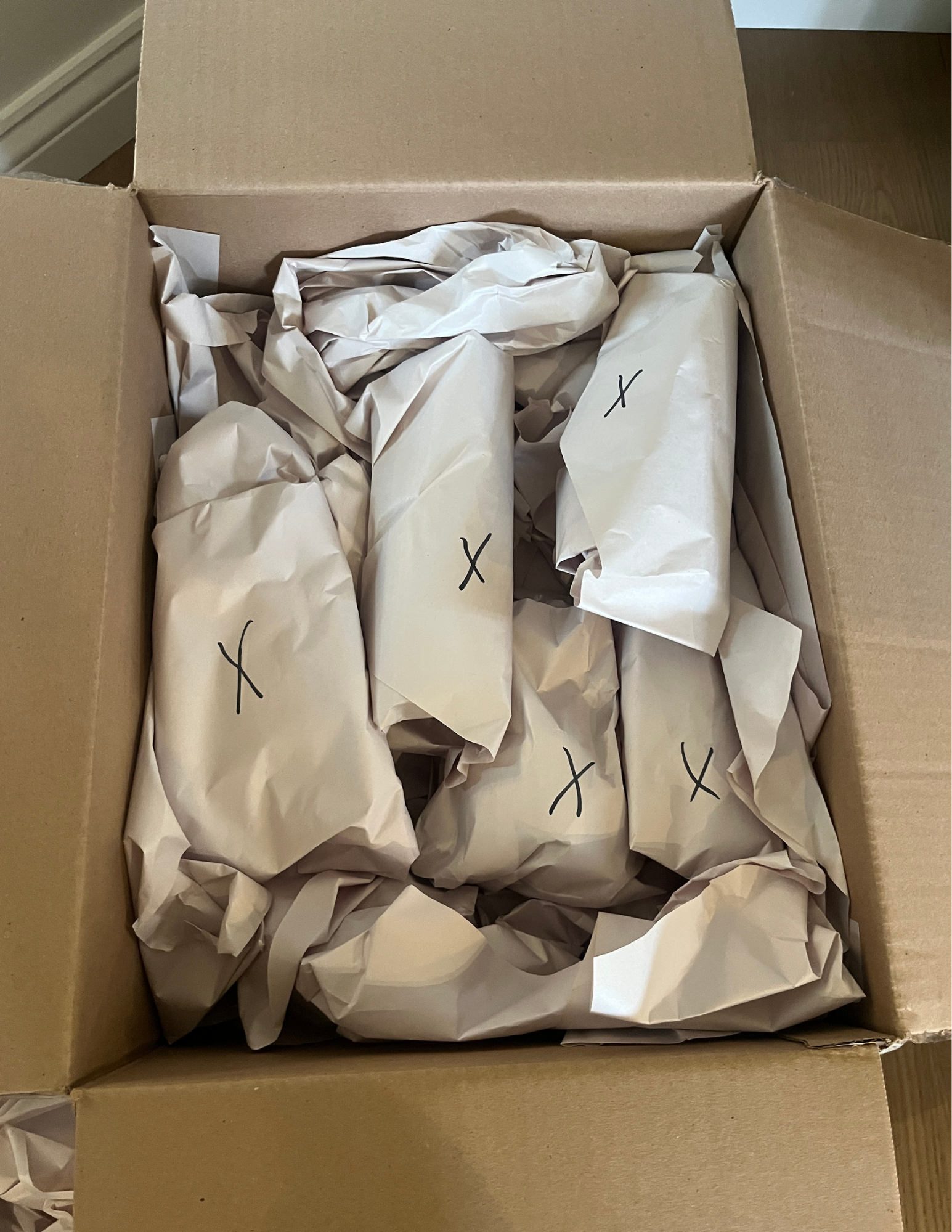Open cardboard box with contents surrounded by packing paper.